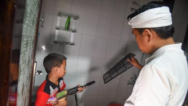 Dedi Mulyadi membantu M Rizky membersihkan komponen AC yang sedang diperbaiki. (FOTO: ISTIMEWA)