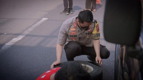 Kapolres Karawang AKBP Aldi Subartono saat mengganti ban mobil pemudik yang bocor di Km 57 Tol Japek. (FOTO: Humas Polda Jabar)