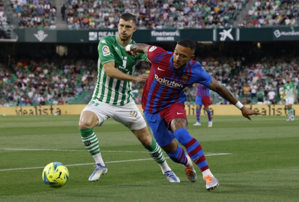 Penyerang Barcelona, Memphis Depay dikawal ketat pemain Real Betis, Guido Rodriguez dalam laga Liga Spanyol 2021/2022 di Stadion Benito Villamarin, Minggu (8/5/2022). (Foto: REUTERS)
