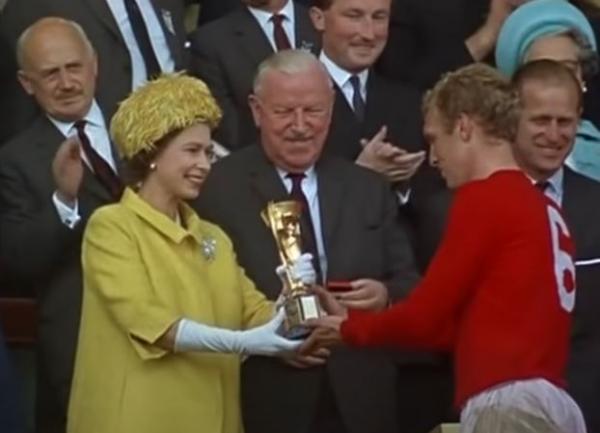 Ratu Elizabeth tampak semringah saat menyerahkan trofi Piala Dunia Jules Rimet kepada kapten Timnas Inggris, Bobby Moore. Pada laga final edisi 1966 itu, Inggris menang 4-2 atas Jerman Barat di final. (Foto: Tangkapan layar YouTube/Sporting History)