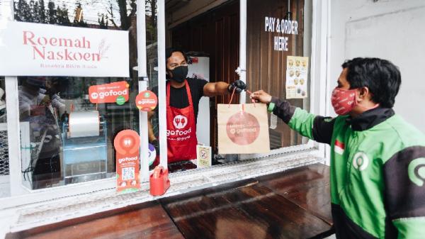 Merchant Gofood menyerahkan makanan kepada driver Goride untuk diantar kepada konsumen yang melakukan pemesanan melalui Gofood. (Foto: istimewa)