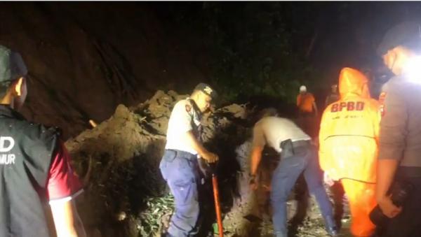 Petugas bersama warga membersihkan material longsor yang menutup jalan Jember-Banyuwangi, Senin (7/11/2022). (Foto: iNews.id/Bambang Sugiarto).