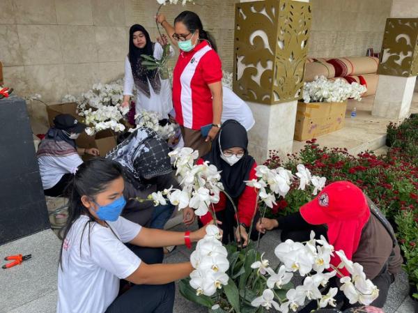Beberapa pegawai Kementerian Sosial sedang merangkai bunga krisan dan anggrek. (Foto: Kemensos)
