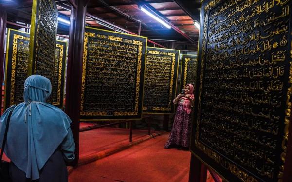 Pengunjung berada di antara lembaran Al Quran terbesar di dunia di Palembang. (Foto: Sindonews)