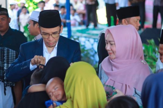 Warga menggendong anaknya antre untuk dipotong rambut oleh Ketua PB NWDI TGB HM Zainul Majdi didampingi Hj Erica Zainul Majdi sebelum tabligh akbar dan halal bihalal di Lapangan Penjor, Desa Genggelang, Kabupaten Lombok Utara, NTB. (Foto: iNews.id/Febri)