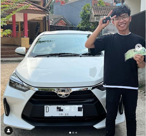 Febbry bersama mobil dan menunjukan STNK miliknya.