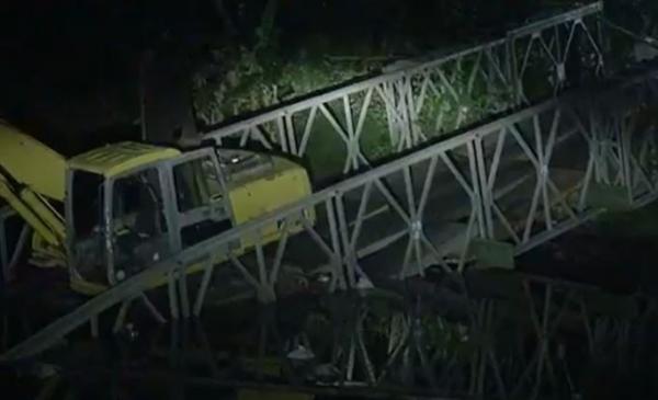 Sebuaah ekskaavaator belum dievakuasi dari Jembatan Bailey di Kali Kemiri, Desa Kupu, Kabupaten Tegal yang ambruk, Minggu (23/7/2023) malam. (Foto: iNews/Yunibar)