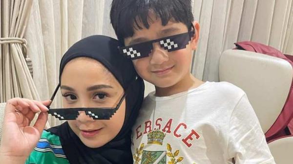Mengenakan hijab hitam sambil memeluk putranya
