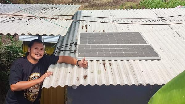 Khilmi Sabihisma mengecek panel surya yang terpasang di atap warung kopi.
