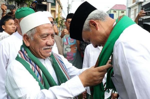 Capres nomor urut 03 Ganjar Pranowo dikalungi serban hijau dari putra Mbah Moen, Gus Ubay. (Foto: MPI)