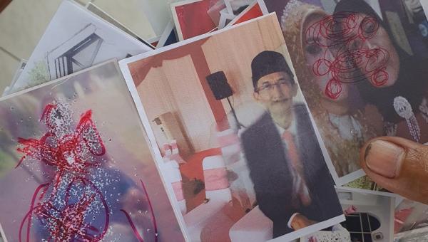 Berikut penampakan foto-foto ditusuk jarum dan dicoret tinta merah yang ditemukan di rumah terduga dukun santet di Tangsel. (Foto: Hambali)