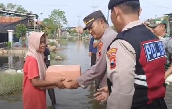 Kapolsek Ulujami, AKP Teguh Hadi Santoso menyerahkan bantuan ke korban banjir rob. (Foto: iNews)