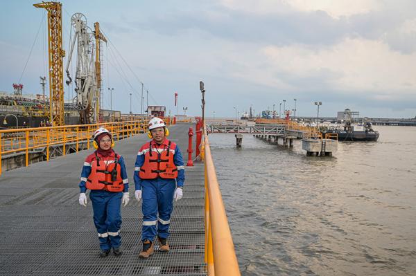 Dua petugas berjalan di fasilitas pelabuhan/jetty di Kilang Pertamina Internasional Unit Dumai, Kota Dumai, Riau.