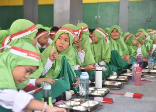 Siswa Madrasah Ibtidaiyah (MI) Al Amin, Jakarta, menikmati menu Makan Bergizi Gratis (MBG). (Foto: Kemenag)
