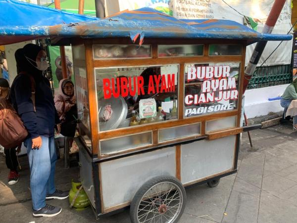 QRIS BRI semakin diminati pelaku usaha kecil, termasuk pedagang bubur ayam di Jakarta yang kini menikmati transaksi lebih praktis dan cepat. (Foto: Reynaldi Hermawan/iNews.id)