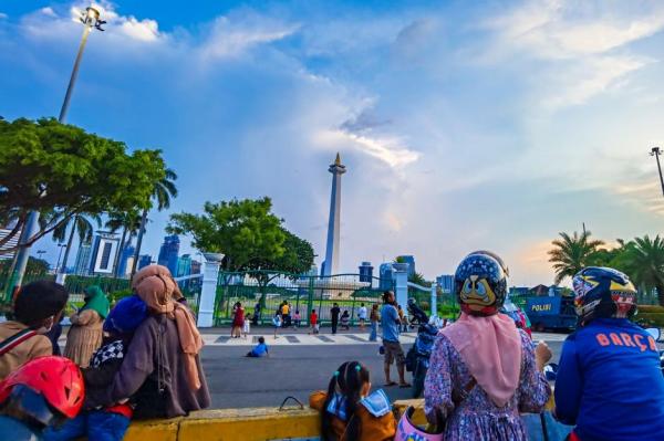 Warga Nikmati Monas Dari Luar Pagar. Monumen Bersejarah Itu Masih Jadi Magnet Para Wisatawan Lokal