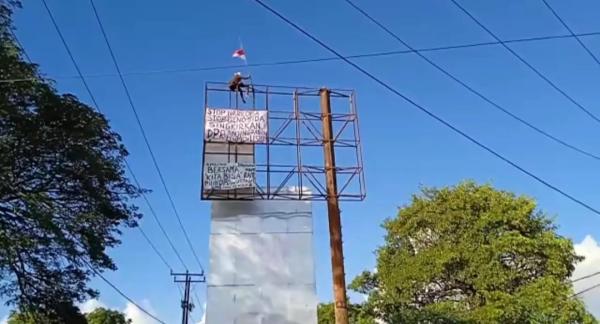 Viral! Seorang Pria di Sikka Panjat Papan Reklame Sambil Bawa Bendera Merah Putih