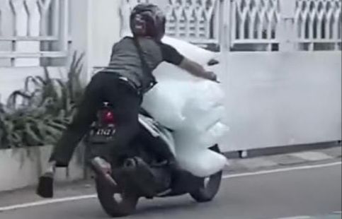 Aksi Pria Kendarai Motor Bawa Tumpukan Karung Es Batu Bikin Heboh Media Sosial