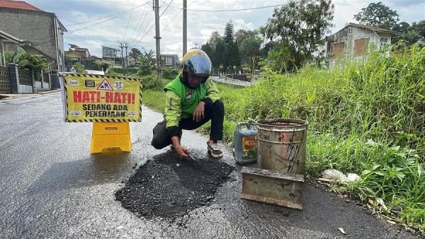 Viral! Driver Ojol di Bandung Tambal Jalan Berlubang Pakai Uang Pribadi, Ini Alasannya