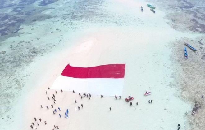 Prajurit Lantamal VIII Manado Bentangkan Merah Putih di Pasir Timbul Pulau Nain