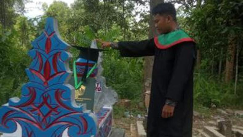 title Penuh Haru, Wisudawan di Makassar Pasang Toga di Makam Sang Ayah Penuh Haru, Wisudawan di Makassar Pasang Toga di Makam Sang Ayah