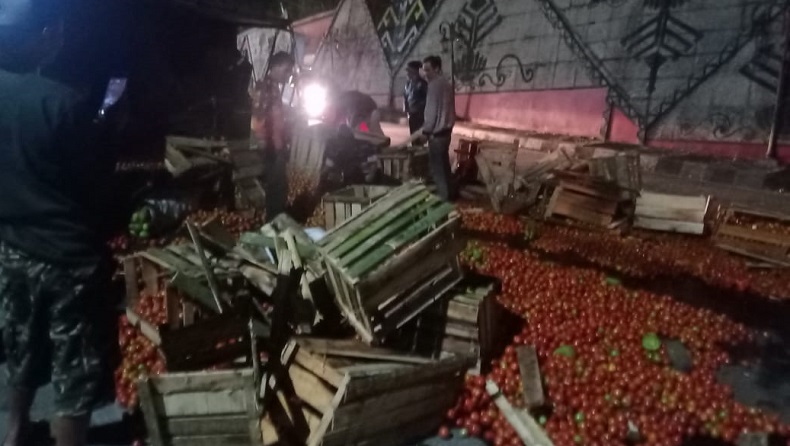 Tomat dan sayuran berserakan di jalan setelah truk terguling di jalan lintas nasional, tepatnya di depan SPBU Liwa, Kabupaten Lampung Barat, Provinsi Lampung, Jumat (29/1/2021) malam. (Foto: iNews/Enrico Ngantung)