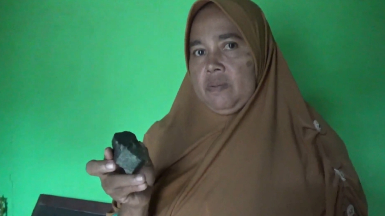 Satinem warga Kampung Mojopahit, Kecamatan Gunungsugih, Lampung Tengah menunjukkan batu diduga meteor (Roy M Paleoli)